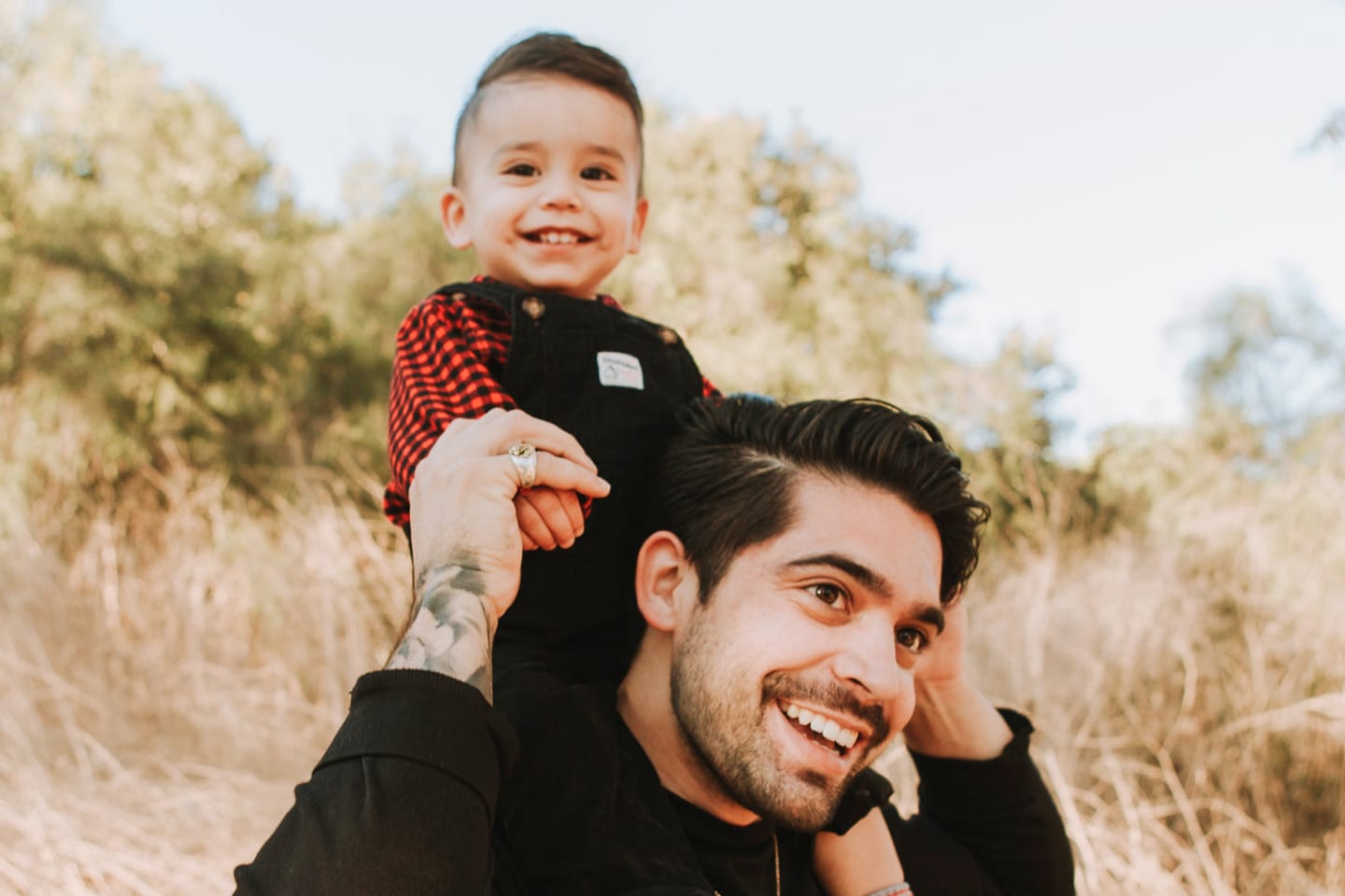 Photograph of a father giving his son a piggy-back ride in the middle of a field